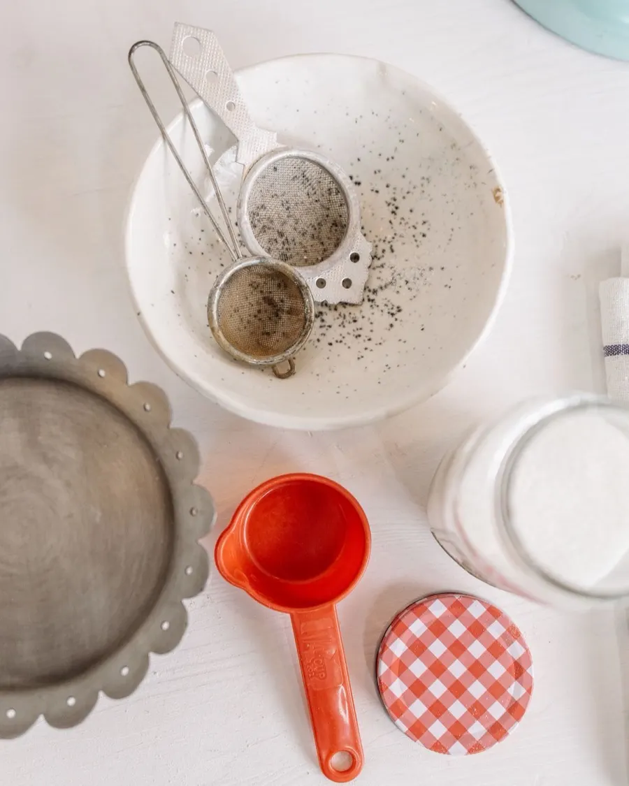 Overhead view of baking bowls, a flour sifter, and a measuring cup laid out on a kitchen counter
